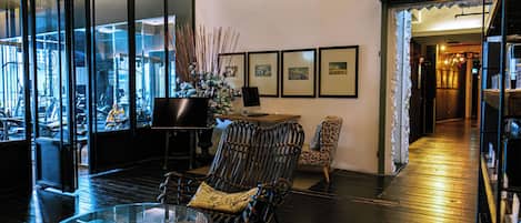 A modern interior with a glass table, wicker chairs, and framed artwork on the wall.