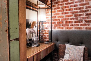 Una habitación con pared de ladrillo, mostrador de madera, lámpara, almohada con mapa y estatua de caballo.