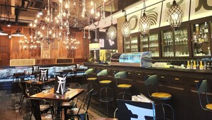 A restaurant interior with multiple tables and chairs, a bar area with glassware, and a variety of hanging light fixtures. - M Boutique Hotel (Ipoh)