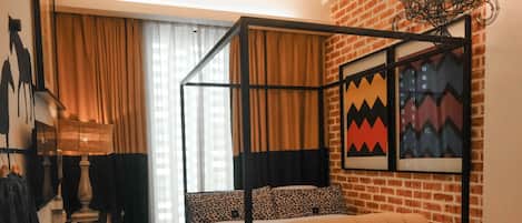 Una cama con dosel y dosel capitonado, un sofá de cuero y una mesita con un teléfono.