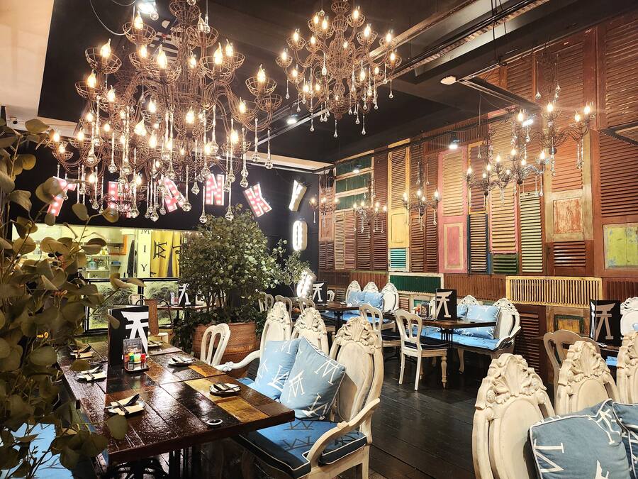 Un interior de restaurante con candelabros ornamentados, paneles de madera y muebles de estilo chino tradicional.