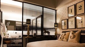 A modern bedroom with a large bed, a vanity with a mirror, and a window with blinds. - M Boutique Hotel (Ipoh)