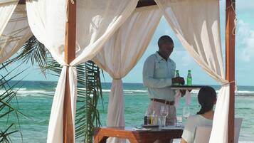 Un montaje para comer frente al mar, con un toldo, una mesa y sillas, con vista al océano.