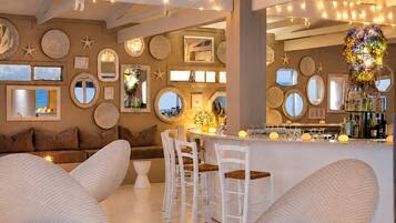 Un interior moderno con una zona de bar, asientos con sillas acolchadas y espejos decorativos en la pared.