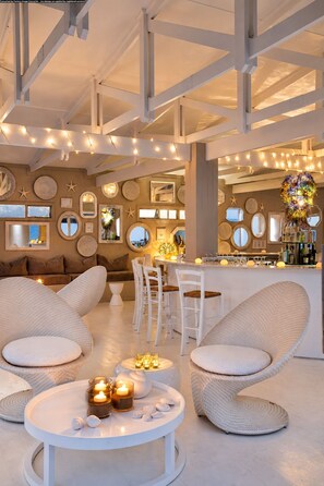 A modern interior with a bar area, seating with cushioned chairs, and decorative wall mirrors. - White Pearl Resorts (Zitundo)