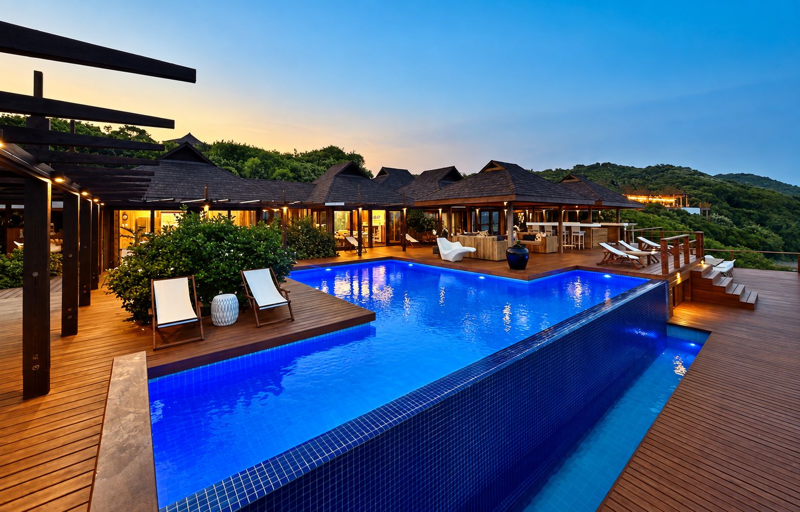 A swimming pool with lounge chairs and a wooden deck, surrounded by overwater bungalows with wooden roofs.