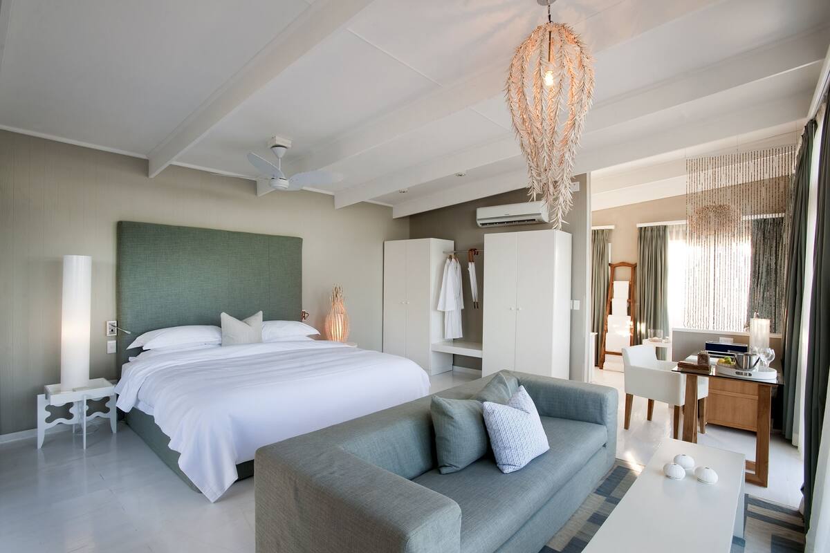 Ein modernes Hotelzimmer mit einem großen Bett, einer Couch, einem Schreibtisch und einem Kleiderschrank.