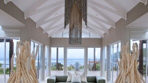 A spacious room with a glass ceiling, a green sofa, and decorative wicker furniture. - White Pearl Resorts (Zitundo)