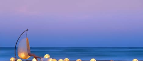 A beach scene with a swing chair and several lit lanterns.