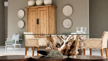 Un comedor con una mesa de vidrio, sillas de madera, un mueble de madera y platos decorativos en la pared.