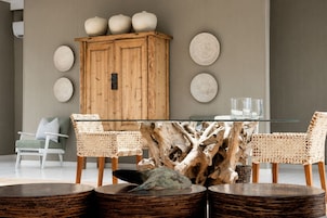 Un comedor con una mesa de vidrio, sillas de madera, un mueble de madera y platos decorativos en la pared.