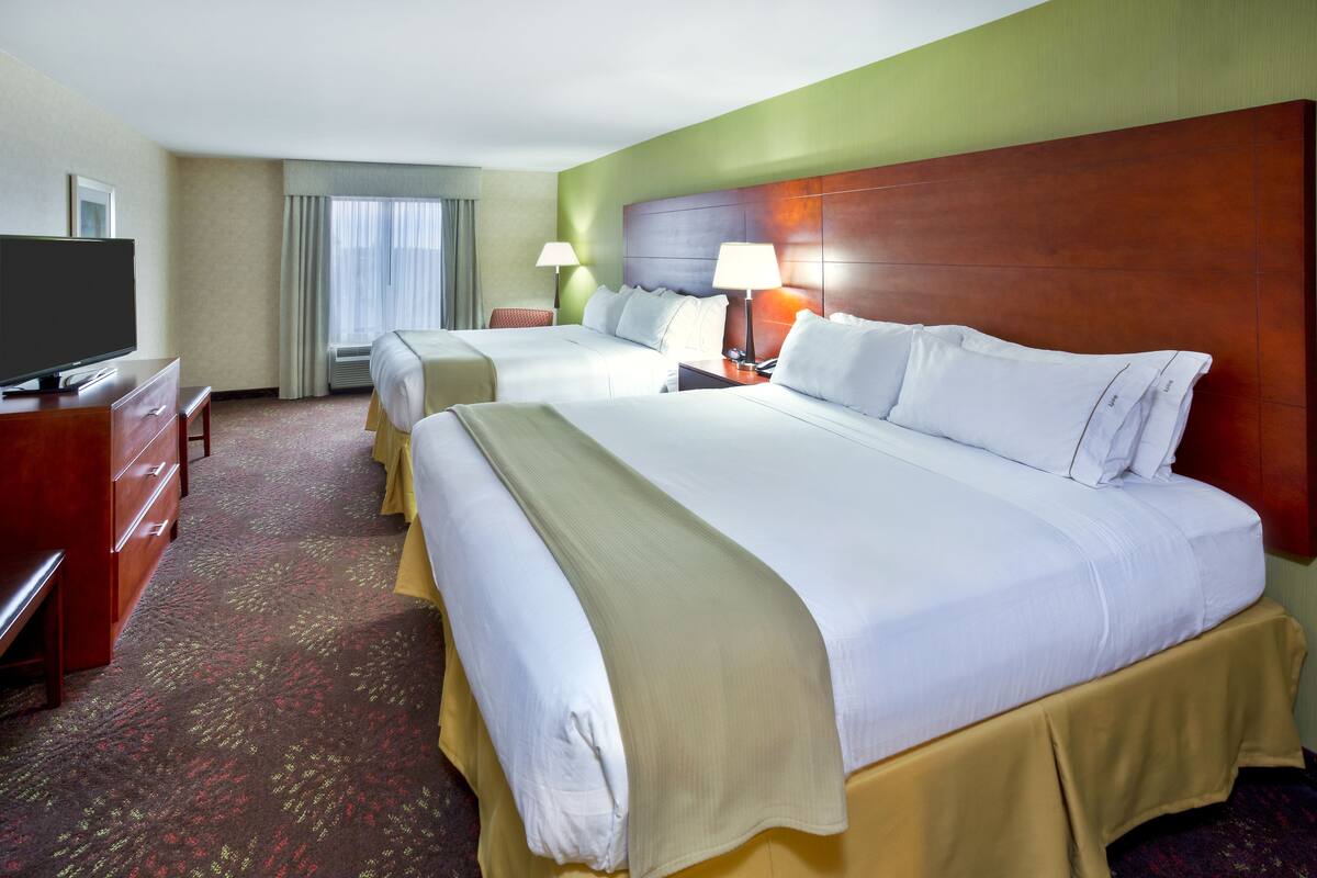 A hotel room with two beds, a television, a desk, and a lamp.