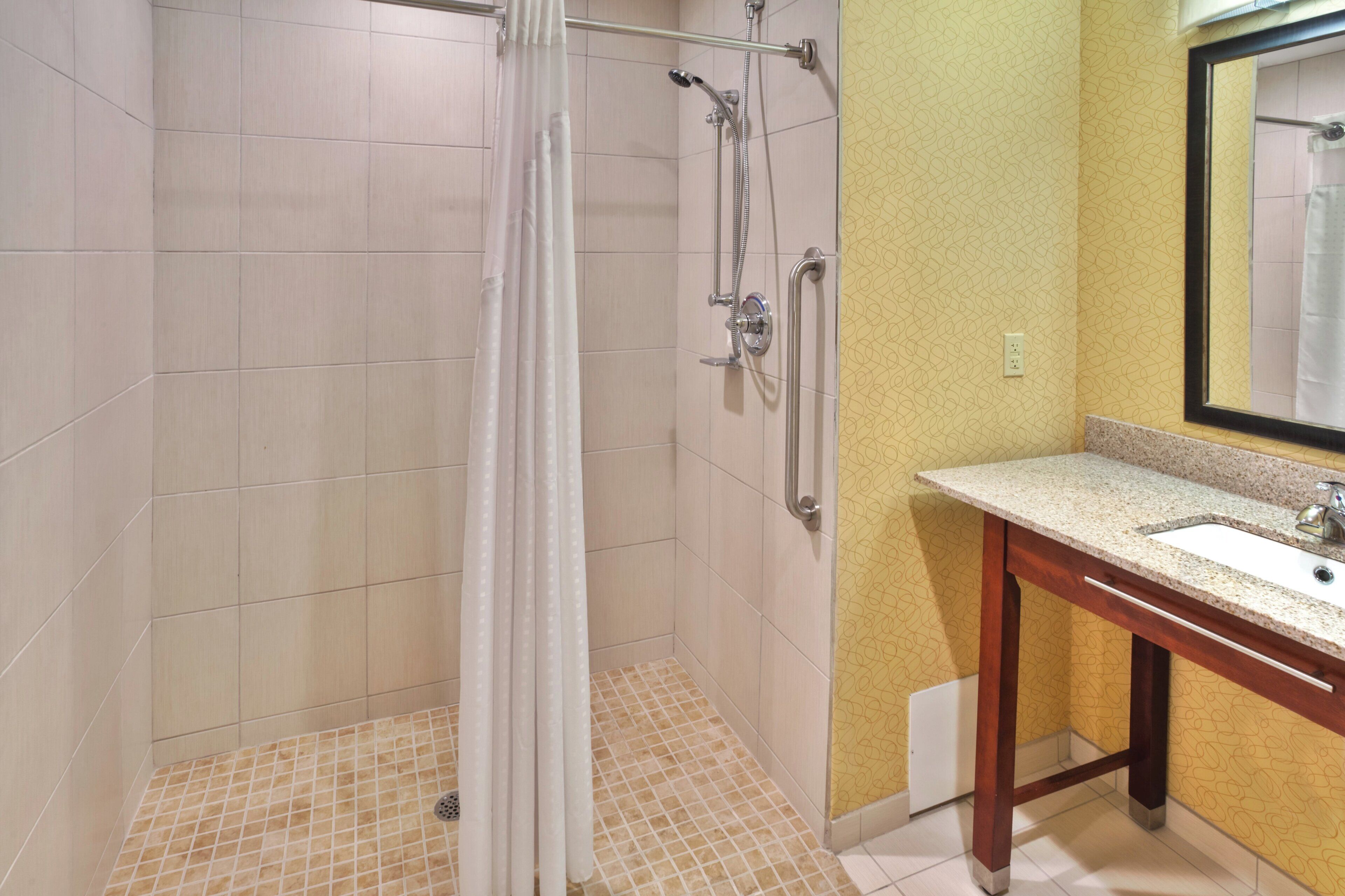 Ein Badezimmer mit Dusche, Waschbecken und Spiegel.