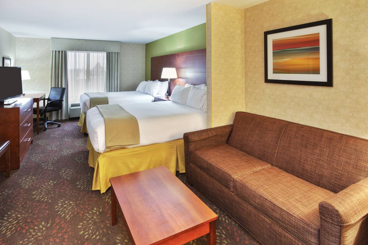 A hotel room with a bed, a sofa, a desk, and a television.