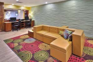 A hotel lobby with a sectional sofa, a reception desk, and a patterned carpet. - Holiday Inn Express Hotel & Suites Frankenmuth by IHG (Frankenmuth)