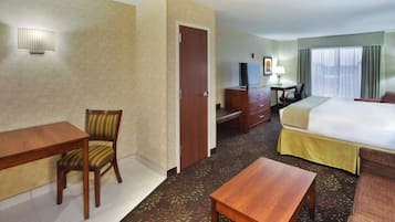 Ein Hotelzimmer mit Bett, Schreibtisch, Stuhl, Fernseher und Lampe.