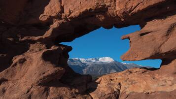 A natural rock formation with a clear view of snow-capped mountains in the background.