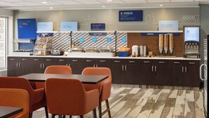 A modern breakfast area with a counter, seating, and various food stations. - Holiday Inn Express & Suites Colorado Springs Central by IHG (Colorado Springs)