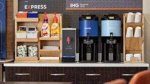 A coffee station with two coffee makers, a hot water dispenser, and a coffee station sign. - Holiday Inn Express & Suites Colorado Springs Central by IHG (Colorado Springs)