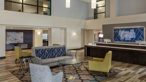 A spacious lobby with a reception desk, seating area, and a high ceiling with pendant lighting. - Holiday Inn Express & Suites Colorado Springs Central by IHG (Colorado Springs)