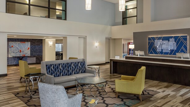 A spacious lobby with a reception desk, seating area, and a high ceiling with pendant lighting. - Holiday Inn Express & Suites Colorado Springs Central by IHG (Colorado Springs)
