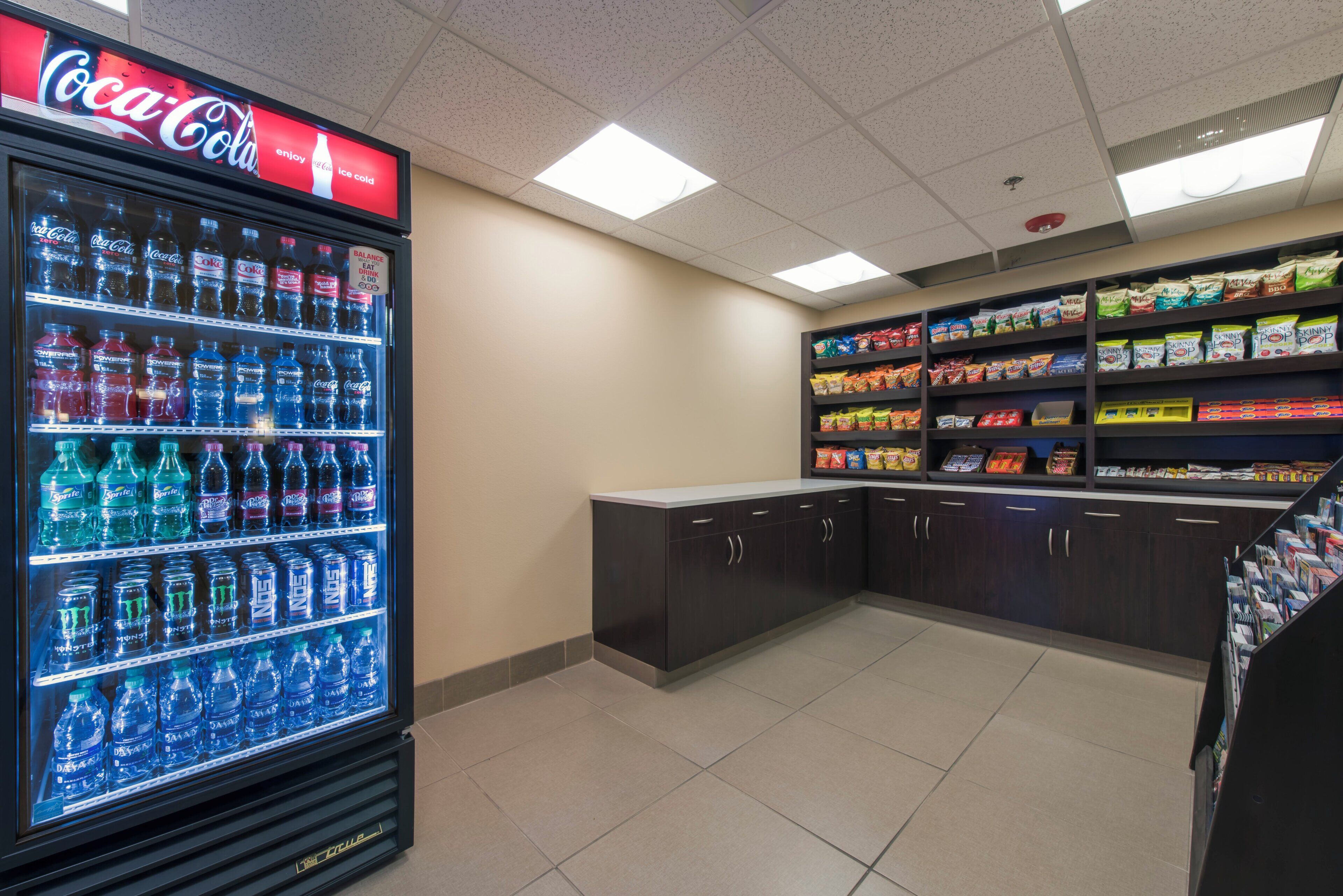 A vending area with a Coca-Cola cooler and shelves stocked with snacks and beverages.