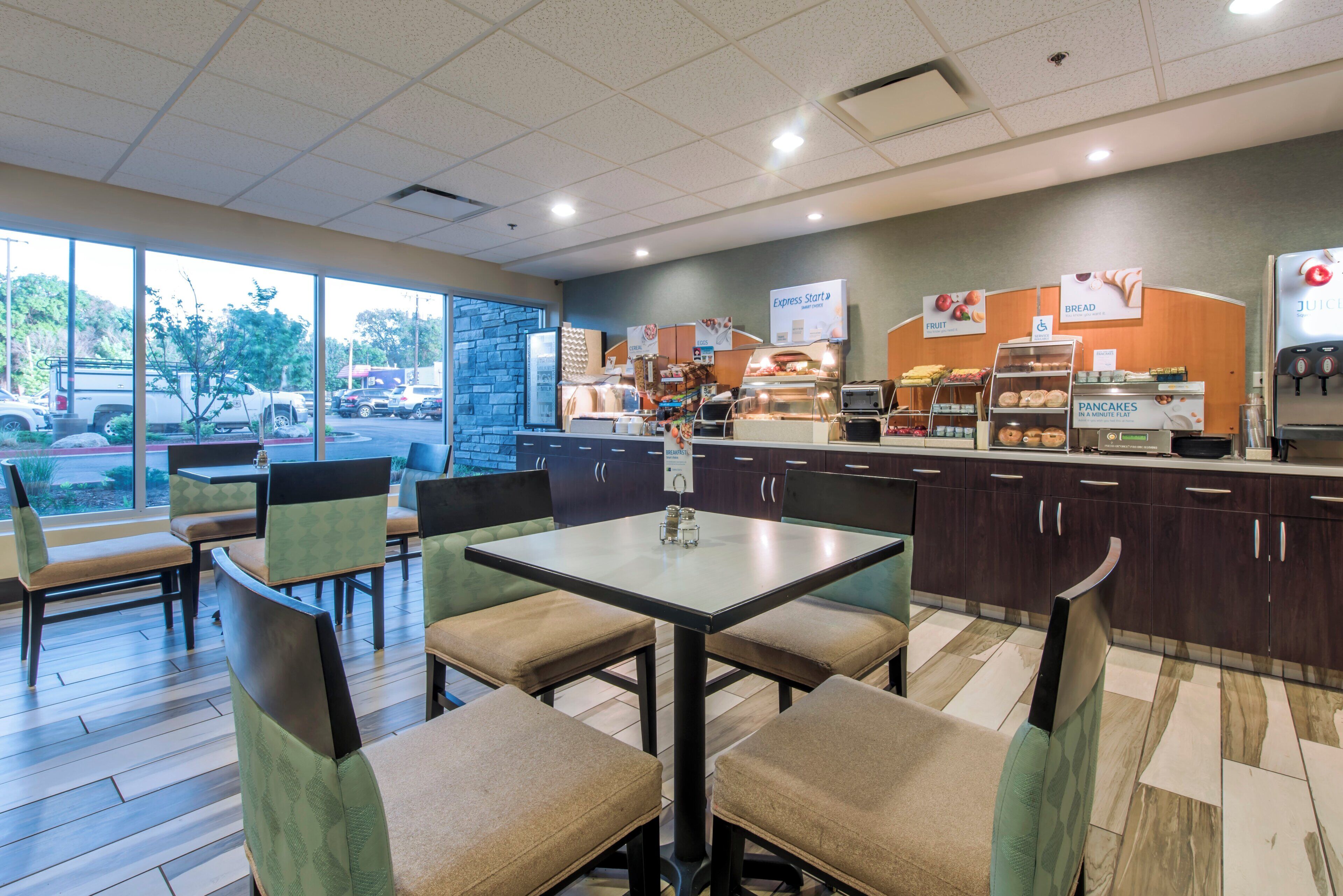 A restaurant with a counter, seating area, and a view of the parking lot.