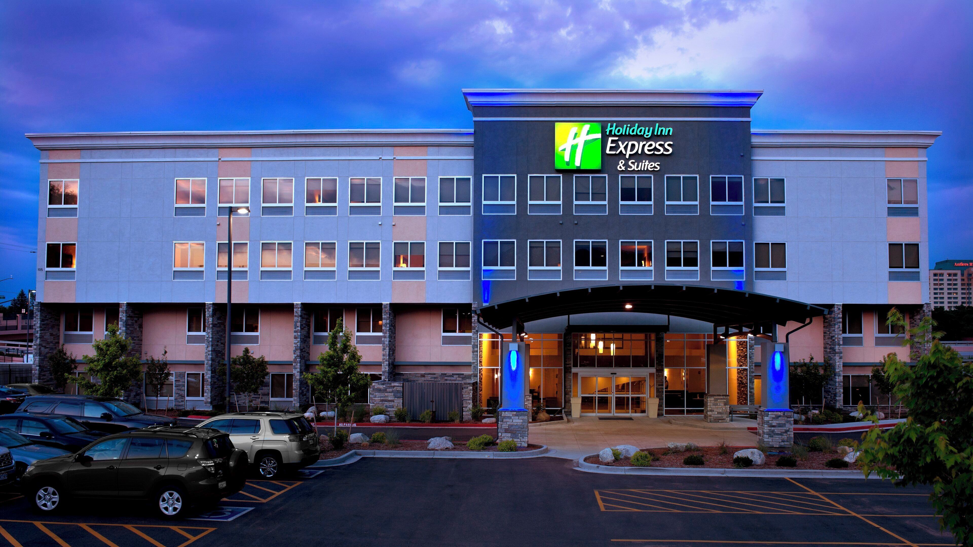 A Holiday Inn Express & Suites hotel with a modern facade, multiple entry points, and a parking lot.