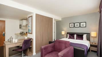 A hotel room with a bed, desk, chair, and a wardrobe.
