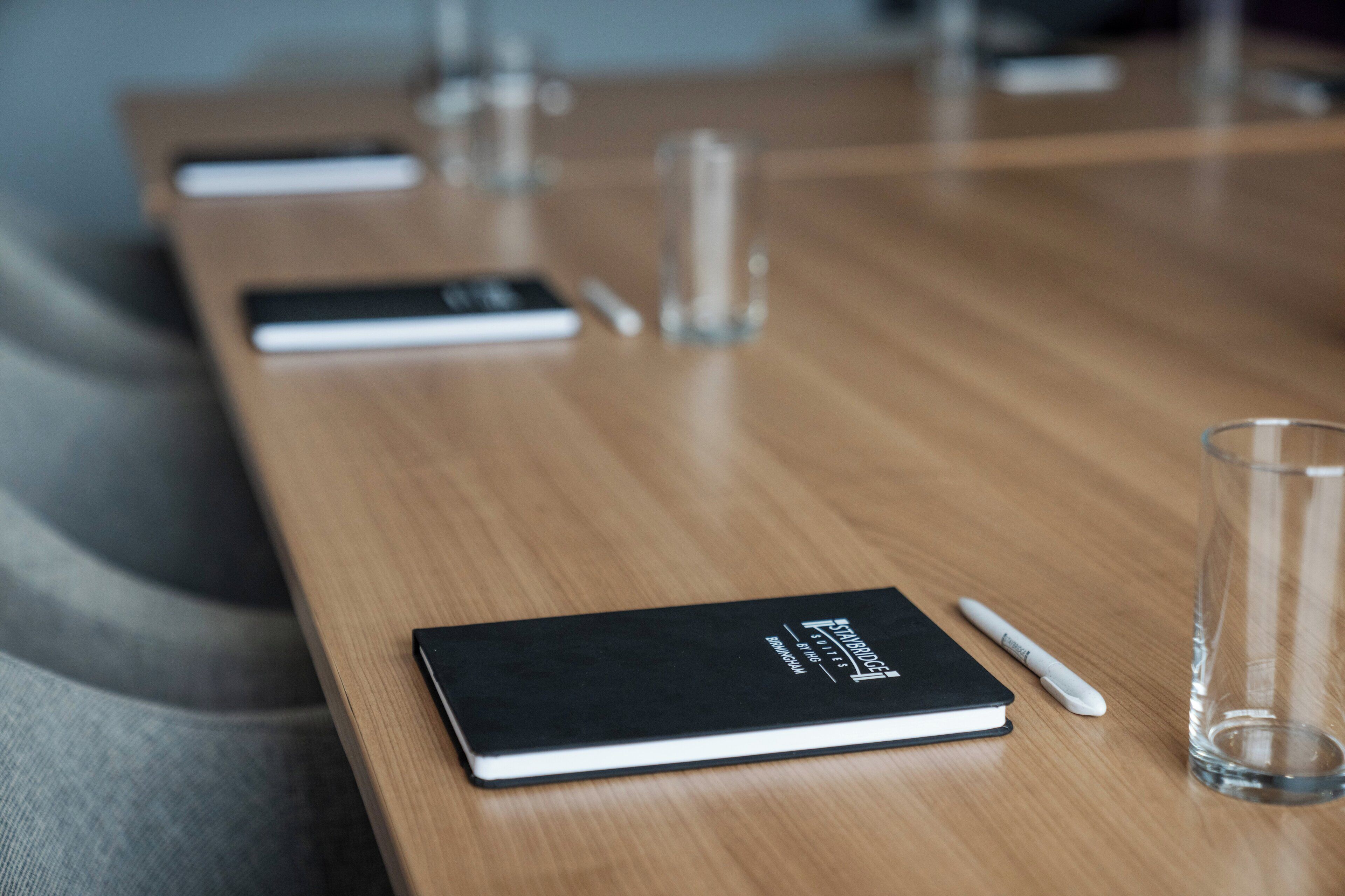 A conference table with a notebook, pen, and glass.