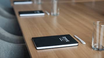 A conference table with a notebook, pen, and glass.