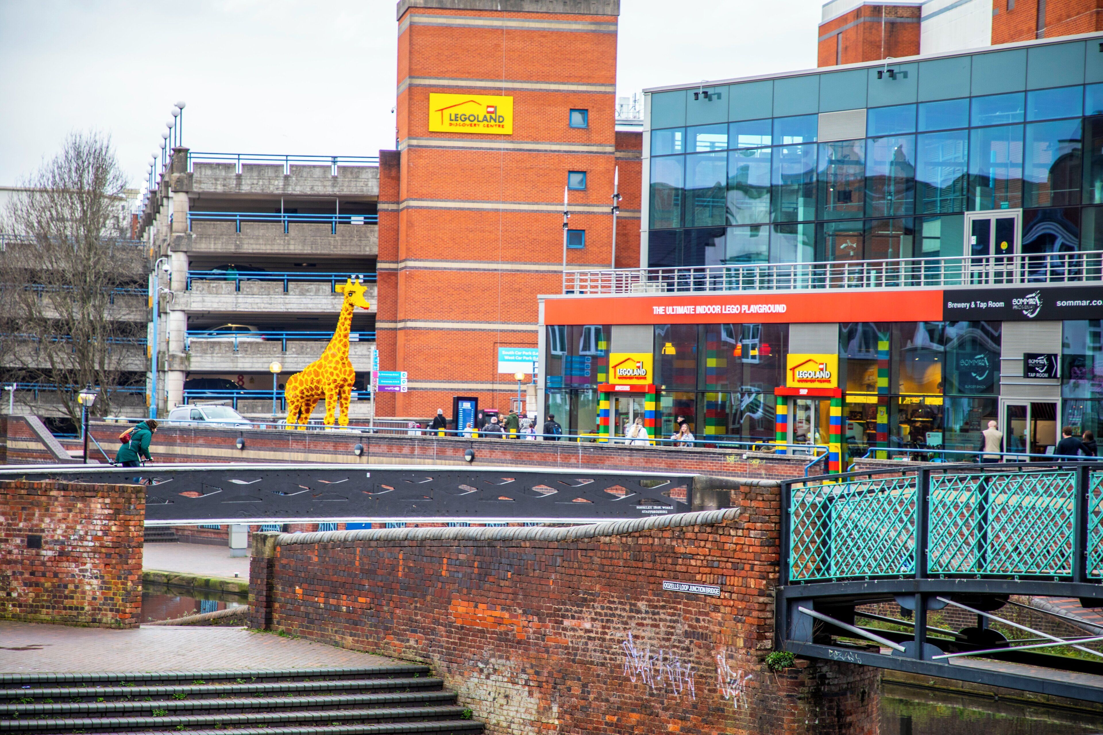A brick building with a yellow giraffe sculpture in front.