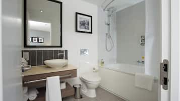 A modern bathroom with a large mirror, a sink, a toilet, and a bathtub.