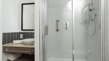 A modern bathroom with a glass-enclosed shower, a white sink, and a mirror above the countertop.