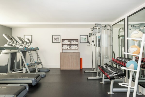 A gym with treadmills, a weight bench, and exercise balls.