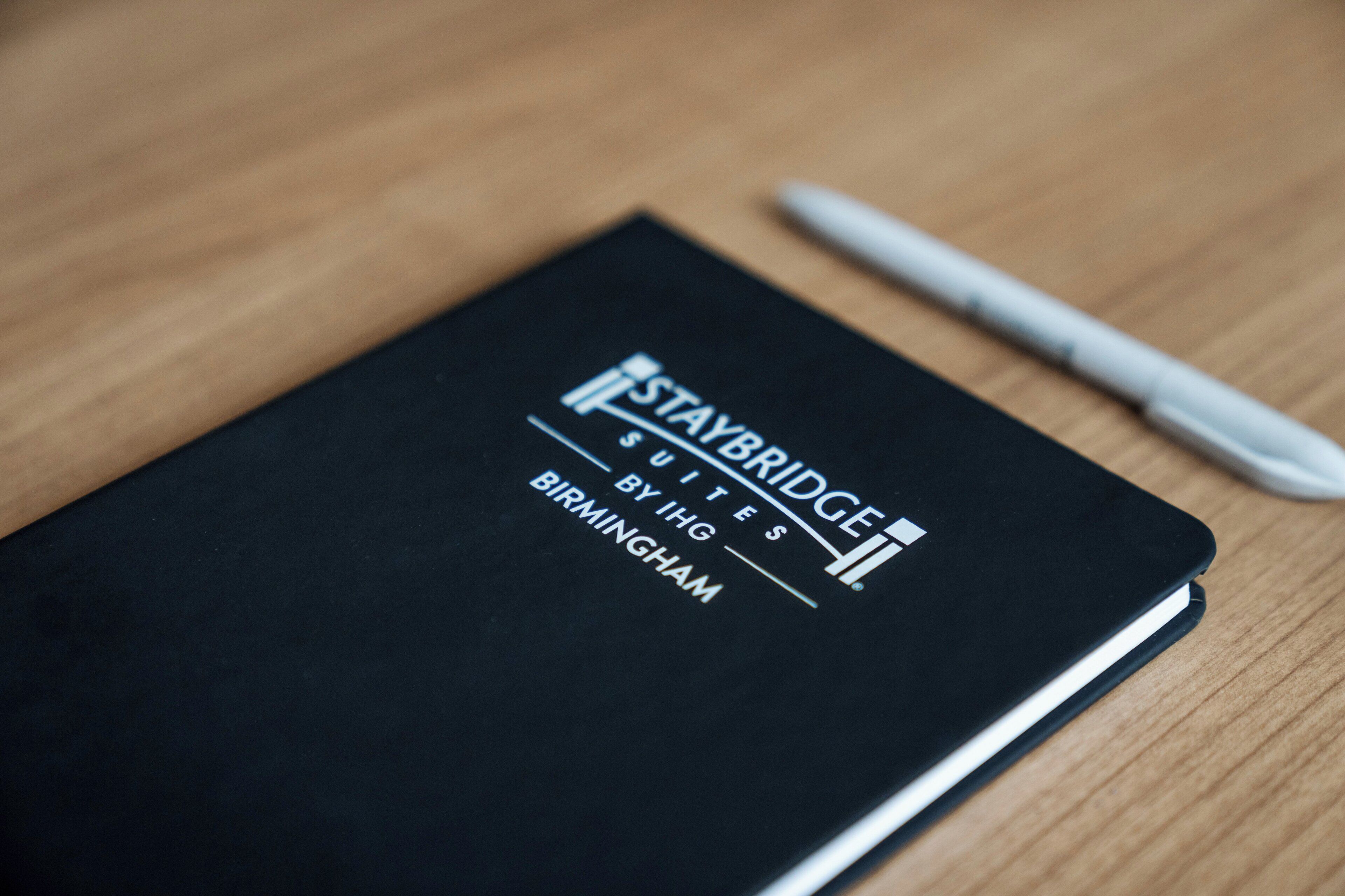 A black notebook with 'STAYBRIDGE SUITES BY HIG BIRMINGHAM' written on the cover.