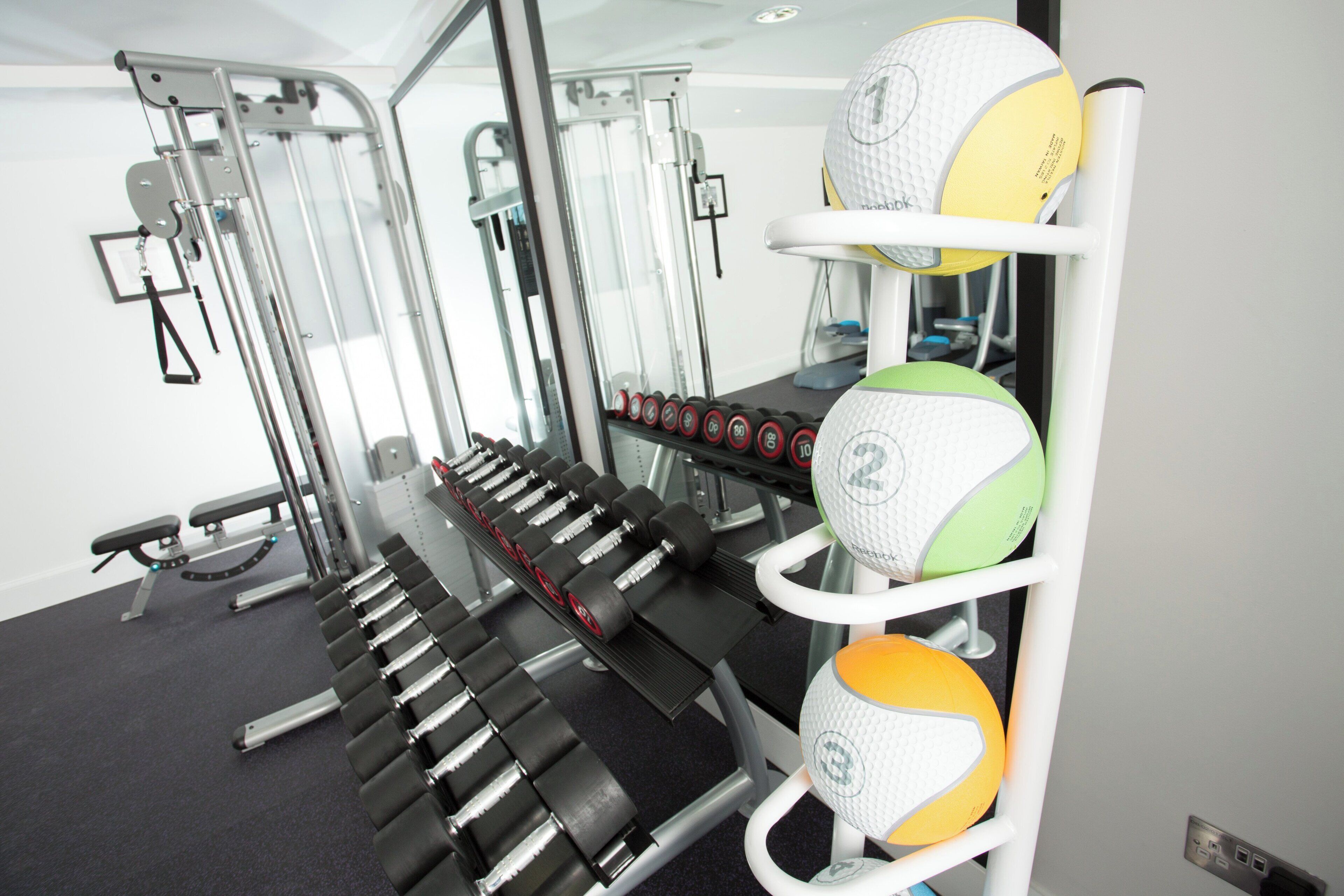 Une salle de sport équipée de matériel d’exercice, notamment des haltères et des balles lestées.