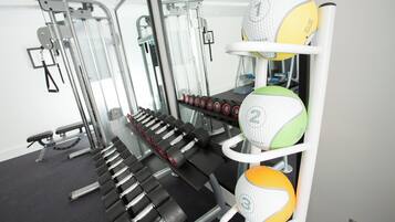A gym with exercise equipment, including dumbbells and medicine balls.