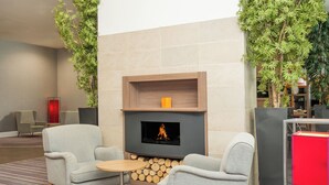 A modern lounge area with a fireplace, comfortable seating, and a stack of firewood. - Staybridge Suites Birmingham by IHG (Birmingham)