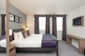 A modern hotel room with a large bed, a desk, a TV, and a window with curtains. - Staybridge Suites Birmingham by IHG (Birmingham)