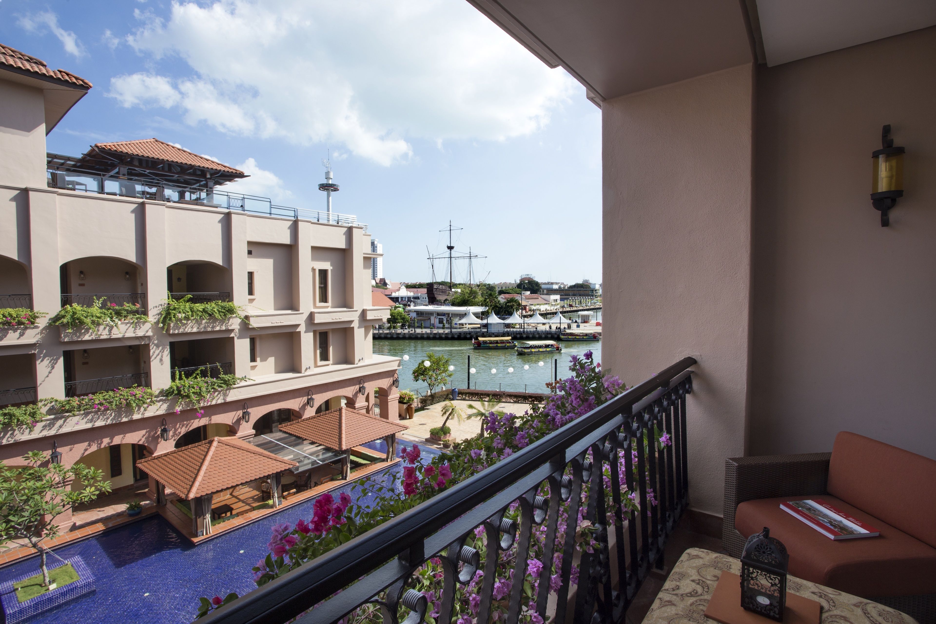 A balcony with a view of a marina, a pool, and a building with arches and balconies.