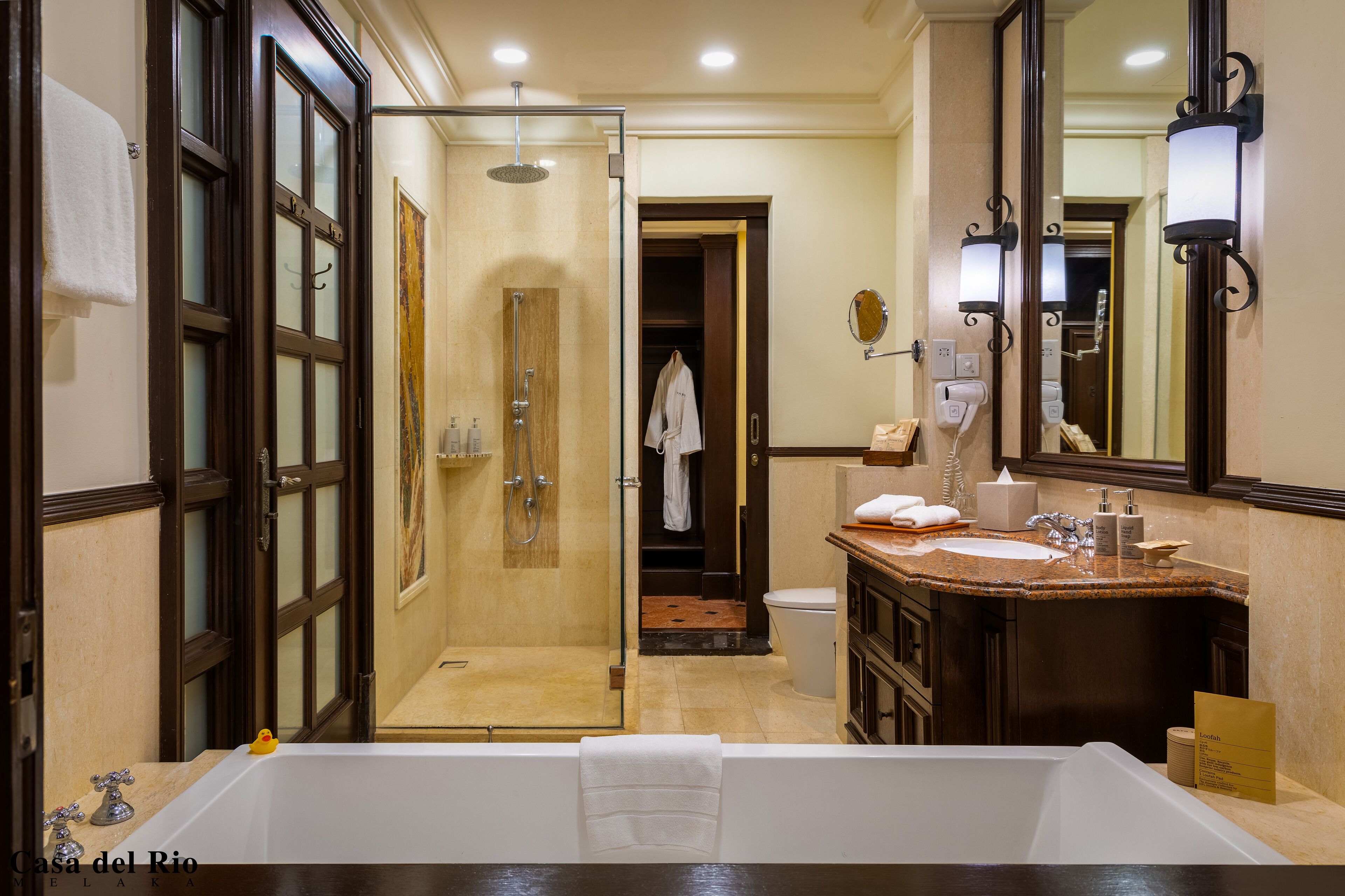 A bathroom with a large bathtub, a glass-enclosed shower, a wooden vanity with a sink, and a mirror.
