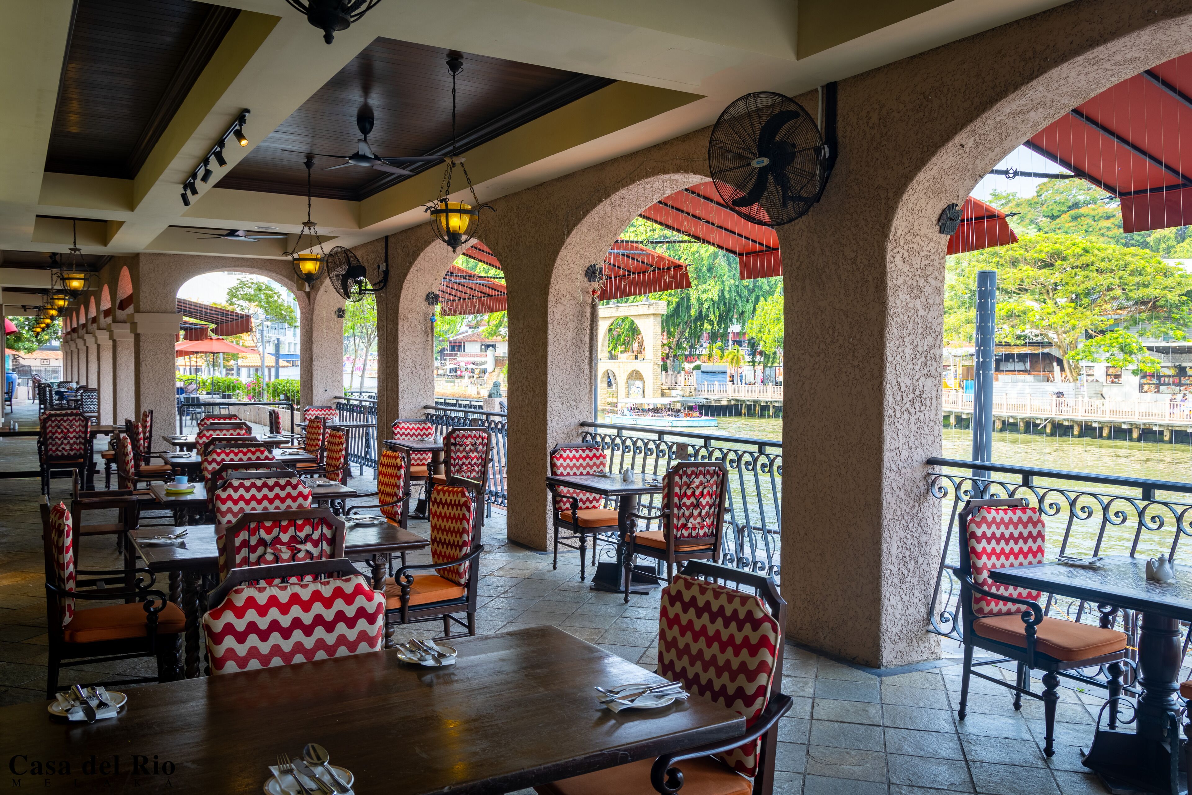 An outdoor restaurant with red and white patterned chairs, tables, and umbrellas.