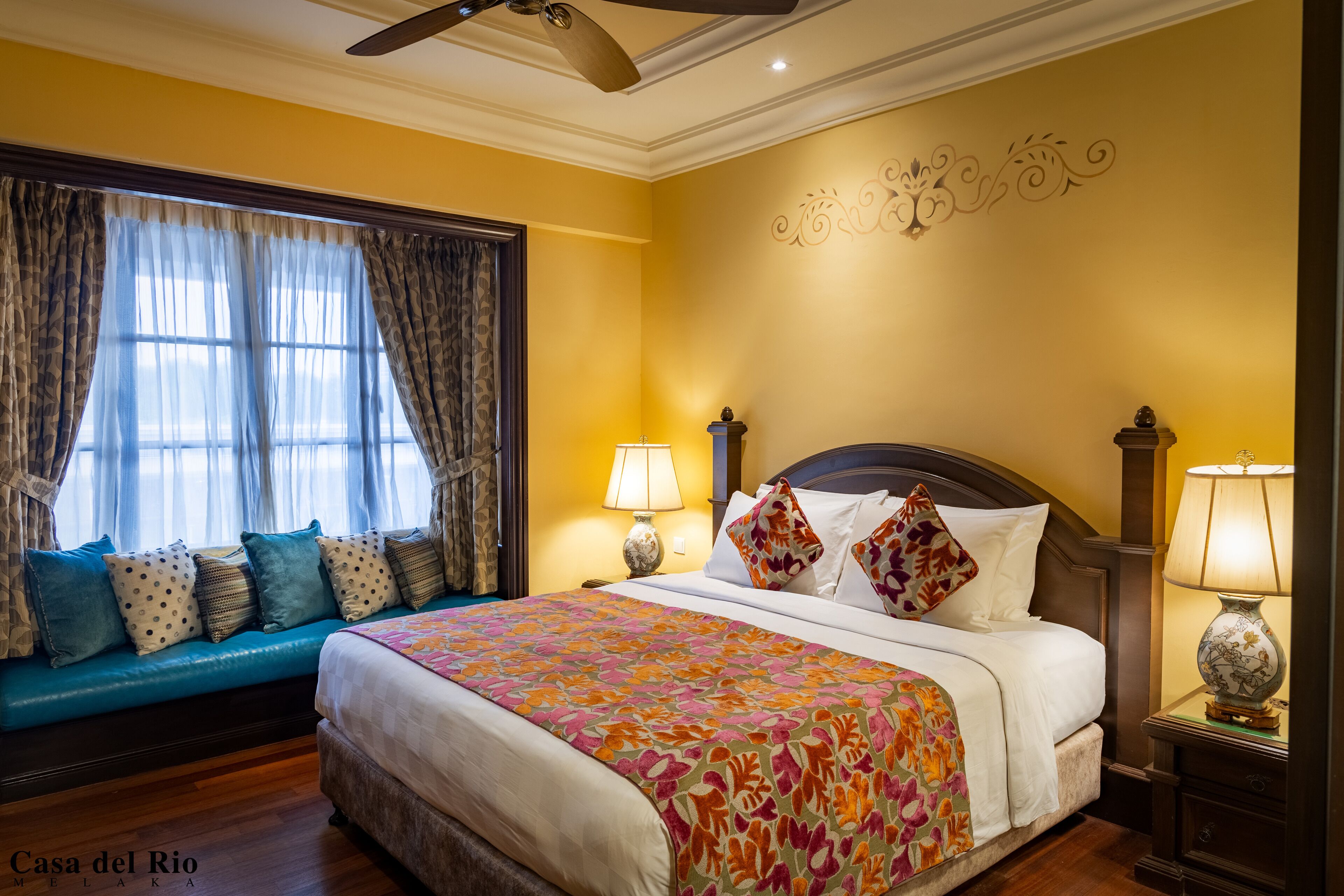 A hotel room with a large bed, a sofa bed, two bedside lamps, and a decorative wall piece.