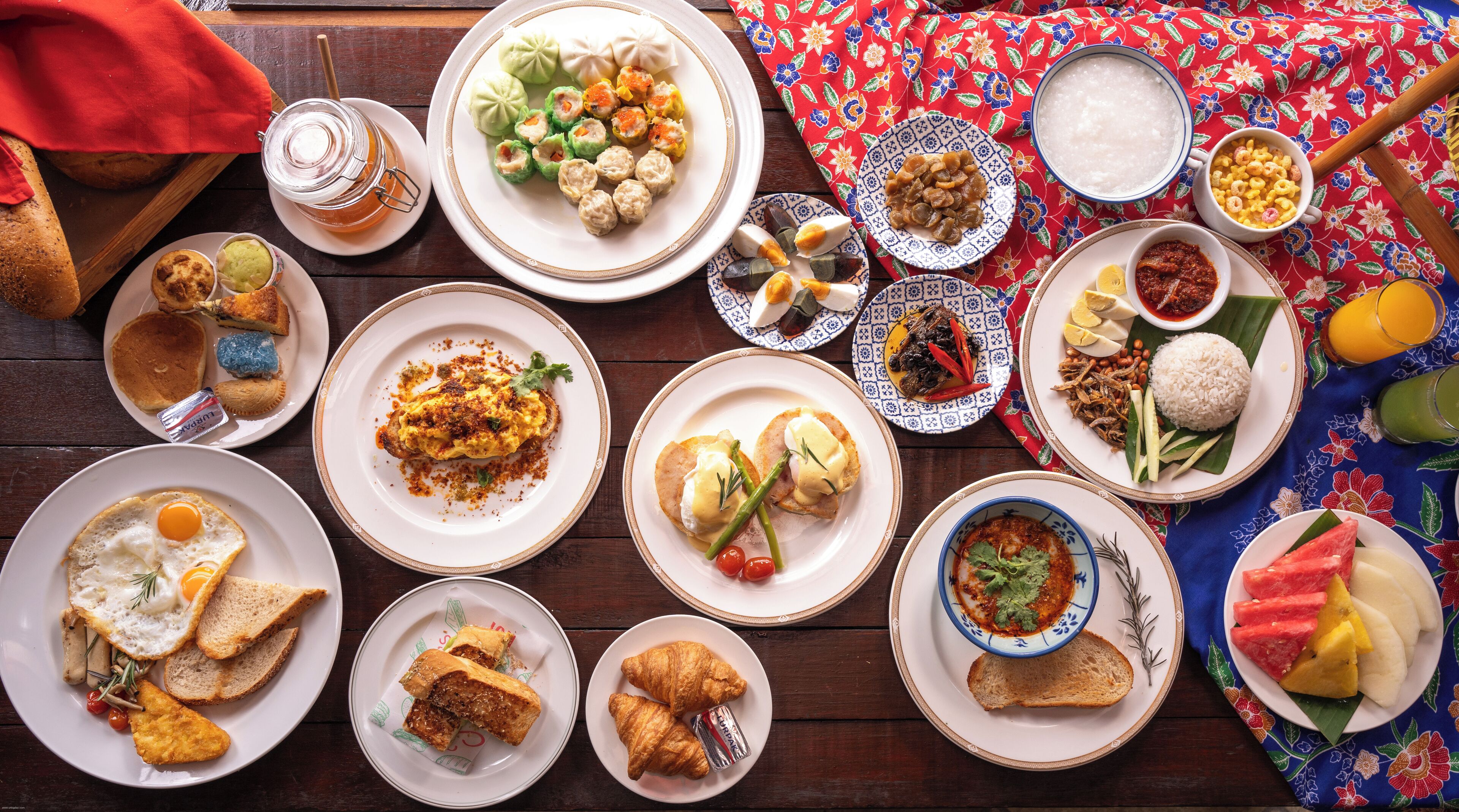 A variety of dishes on a wooden table, including eggs, bread, and various side dishes.