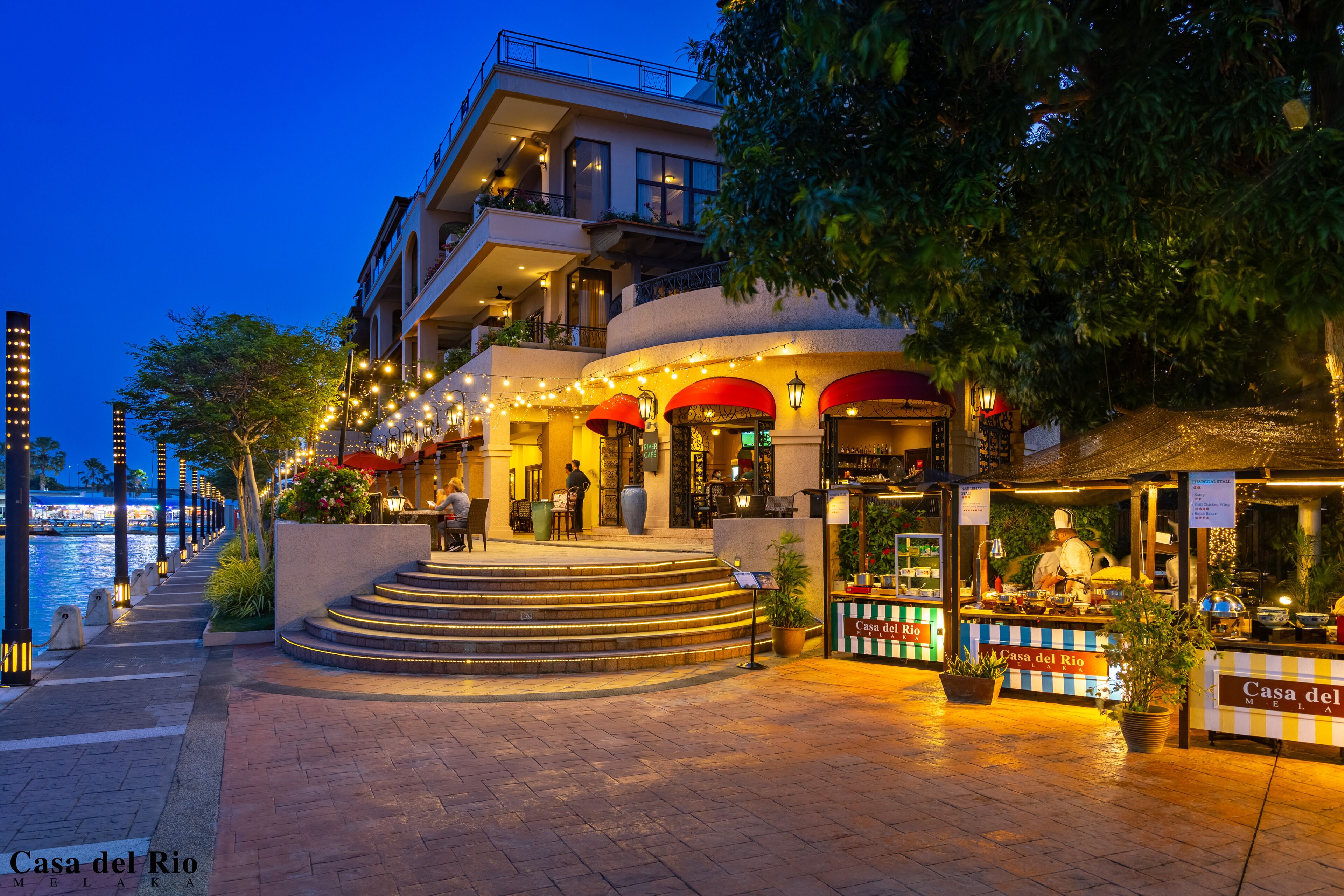 Un hôtel avec vue sur le front de mer, une terrasse et une entrée bien éclairée.