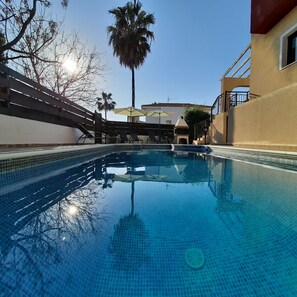 En säsongsöppen utomhuspool, parasoller och solstolar