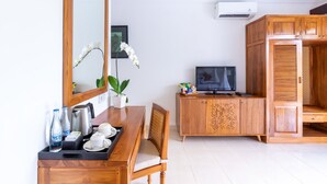 A hotel room with a wooden dining table, chairs, a TV, a cabinet, and a large mirror. - Villa Sonia Bisma (Ubud)