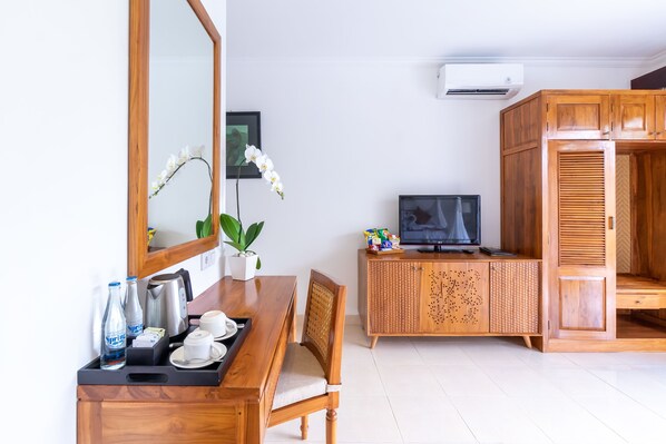 A hotel room with a wooden dining table, chairs, a TV, a cabinet, and a large mirror. - Villa Sonia Bisma (Ubud)