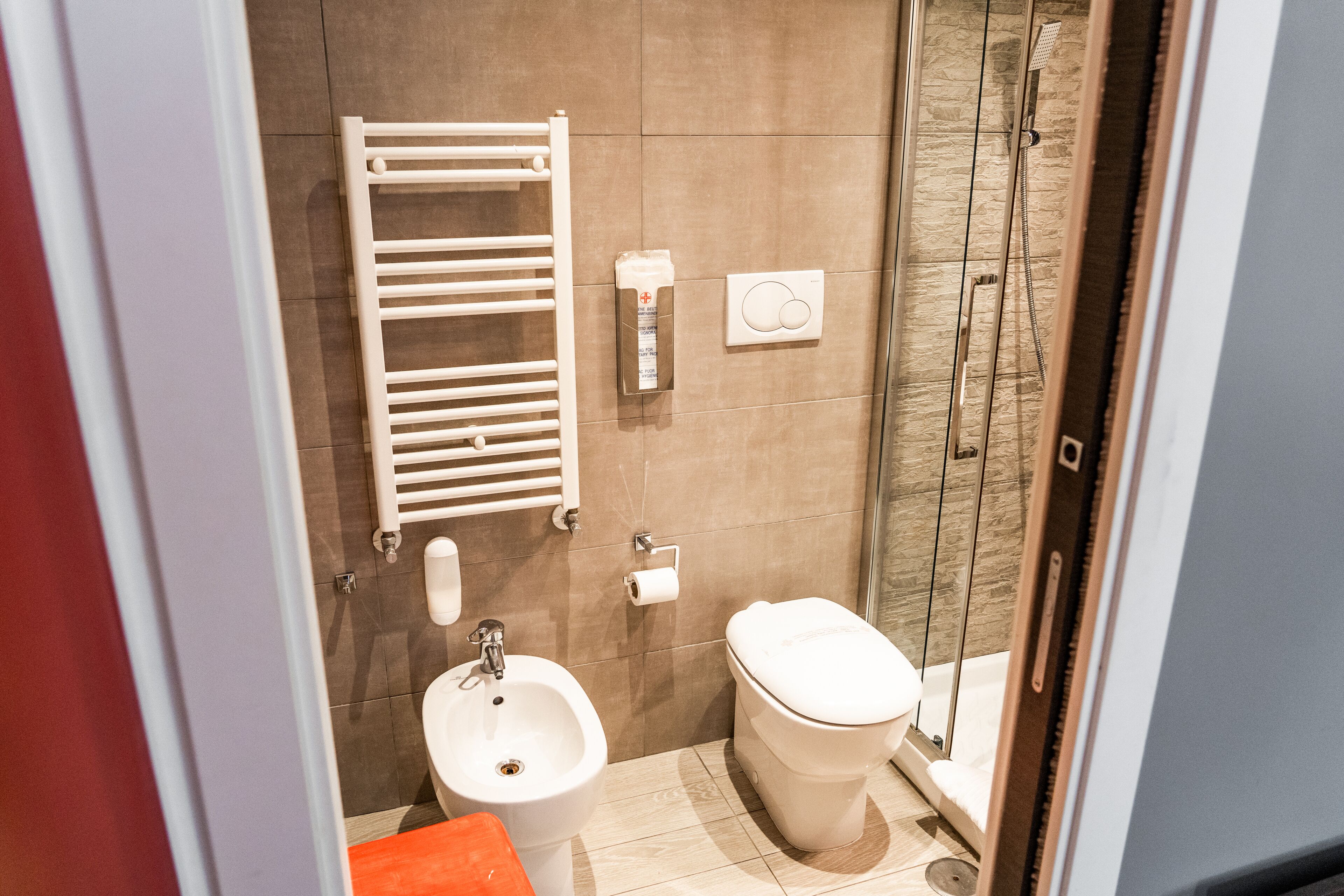 A modern bathroom with a bidet, toilet, and glass shower enclosure.